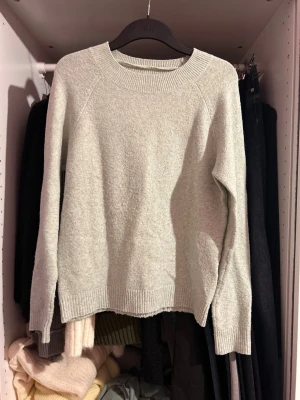 Ljusgrå stickad tröja Vero Moda - Mysig ljusgrå stickad tröja från Vero Moda med rund halsringning och ribbade muddar vid ärmslut och nederkant. Perfekt för lager på lager och enkel att matcha med olika outfits. Tillverkad i mjukt material som känns skönt mot huden.