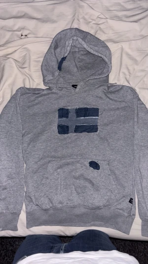 Grå hoodie med handsydd sverige flagga! - En snygg grå hoddie med svenska flaggan hand sydd på, storlek xs-s passar 170-178cm och ungefär 55-68 kilo. 650kr