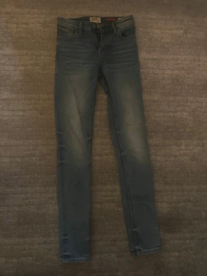 Blå skinny jeans från Crocker - Säljer ett par blå skinny jeans från Crocker med klassisk femficksdesign och dragkedjegylf. Jeansen har en snygg tvätt med slitningar. Perfekta för dig som gillar en smal passform och tidlös stil.
