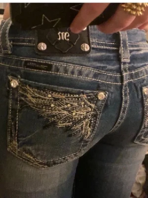Miss Me blå jeans med broderi - Säljer ett par blå jeans från Miss Me med snygga broderade detaljer och nitar på bakfickorna. Säljer för de har blivit för små :(. Super trändiga!