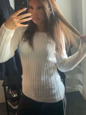 Vit ribbstickad tröja från Bikbok  - Säljer en vit ribbstickad tröja med rund hals och långa ärmar. Tröjan har en figurnära passform och är perfekt för lager-på-lager. Enkel och stilren design som passar till det mesta.