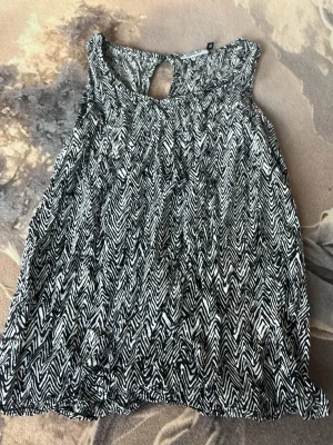Svartvit mönstrad linnetopp från ONLY - Snygg ärmlös linnetopp från ONLY i svartvitt zebramönster. Toppen har en rund halsringning och en liten öppning bak i nacken. Perfekt att styla med jeans eller kjol för en trendig look.