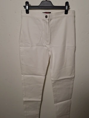 Vita skinny jeans med hög midja - Snygga vita skinny jeans med hög midja och klassisk femficksdesign. Jeansen har raka ben och stängs med knapp och dragkedja. Perfekta att matcha med en crop top eller hoodie. Materialet är stretchigt för extra komfort.