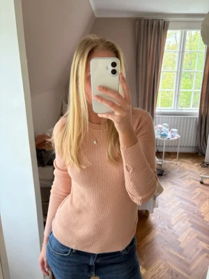 Ljusrosa ribbstickad tröja - Säljer en ljusrosa ribbstickad tröja med rund hals och långa ärmar. Tröjan har en smal passform och är tillverkad i ett mjukt, stretchigt material som sitter snyggt på kroppen. Perfekt att matcha med jeans eller kjol.
