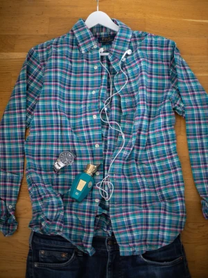 Rutig skjorta från Polo Ralph Lauren - Snygg rutig skjorta från Polo Ralph Lauren i blå, grön och vit färg. Skjortan har klassisk krage, knäppning framtill och lång ärm. Perfekt för en avslappnad men ändå stilren look.
