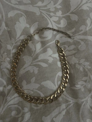 guldfärgat kedje halsband  - Halsband i guldfärgad metall med breda länkar och justerbar kedja. 