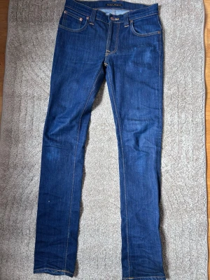 Blå  jeans från Nudie Jeans -  Hej och välkomna till Liljestrands Nu säljer vi ett par jeans från märket nudie De är i bra skick, endast en effekt som syns på bild sex storlek 29 / 34 modell thinn finn kom med frågor och så vidare så hörs vi. MVH Liljestrand