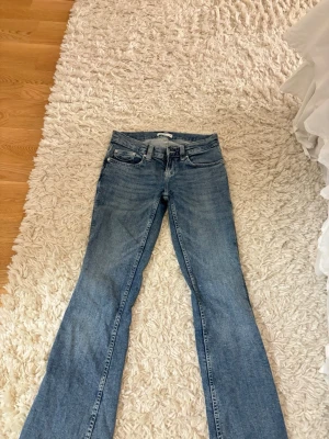 Blå bootcut jeans - Säljer ett par blå bootcut jeans med snygga broderade detaljer på bakfickorna. Klassisk femficksmodell med normal midja och dragkedja. 