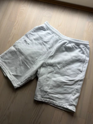 Vita shorts från Replay i bomull - Säljer ett par vita shorts från Replay med elastisk midja och diskret logga på ena benet. Sköna och stilrena, perfekta för sommaren. Tillverkade i mjuk bomull för maximal komfort.