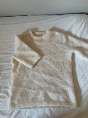 Krämvit stickad tröja H&M mohair - Mysig krämvit stickad tröja från H&M i mohair- och ullblandning. Tröjan har rund halsringning, långa ärmar och ribbade muddar vid ärmslut och nederkant. Perfekt för lager-på-lager och en stilren look.