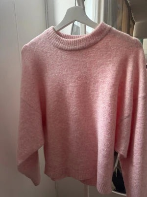 Ljusrosa stickad tröja  - Mysig ljusrosa stickad tröja. Tröjan har långa ärmar. Perfekt för lager-på-lager och en chill look.