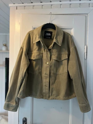 Olivgrön jeansjacka från ZARA - Snygg olivgrön jeansjacka från ZARA med klassisk krage, två bröstfickor med lock och knappar framtill. Jackan har en avslappnad passform och raka ärmar💞 storlek M inga skador🥰