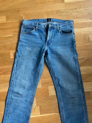 Blå raka jeans från Lee - Säljer ett par klassiska blå jeans från Lee med rak passform och fem fickor. W31, L32