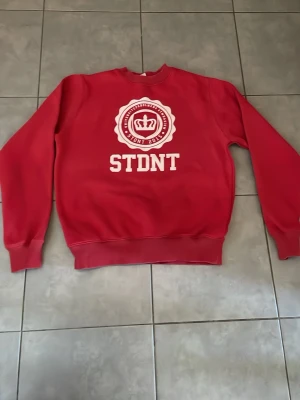 Röd tröja  -  Detta är en röd tröja från universitetsholmens gymnasium från en elev som tog studenten 2015. Den har varit använd väldigt sällan. Tröjan passar väldigt bra med jeans eller jeans shorts.