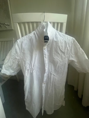 Vit kortärmad skjorta  - Snygg vit skjorta från Whyred med korta ärmar och klassisk krage. Skjortan är tillverkad i bomull och har knappar framtill. Perfekt för en stilren och fräsch look.