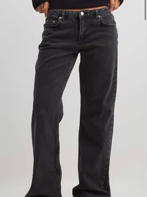 Svarta loose fit jeans med låg midja - Säljer ett par gråa jeans med låg midja och raka, lösa ben. Jeansen har klassisk femficksdesign och är tillverkade i denim. Perfekta för en avslappnad och trendig stil. Använda fåtal gånger. Säljer då de är för stora. Litet hål längst ner på byxorna 