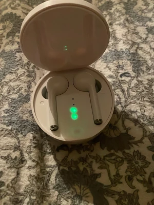 Vita trådlösa in-ear hörlurar - Säljer ett par vita trådlösa in-ear hörlurar med laddningsetui. Hörlurarna har stilren design och laddningsindikator med grönt ljus på etuiet. Perfekta för musik, poddar och samtal. Laddas via USB-port på baksidan av etuiet. Använt bara 5 gånger kanske helt rena. Bra ljud i båda öronen.