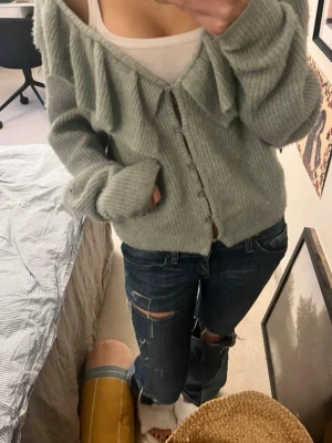 Ljusgrön kofta med volang - Jätte gullig mintgrön kofta från h&m som är slutsåld. En av knapparna är sönder som syns på bild men jag har löst det genom att knyta fast knappen på plats. Så skönt material och inga övriga defekter. Skriv vid frågor 🤗