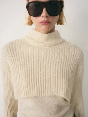 Beige ribbstickad cropped tröja - Trendig beige ribbstickad cropped tröja med hög krage och långa ärmar. Tröjan har en boxig passform och är tillverkad i ett mjukt, tjockare material som ger en snygg struktur. Perfekt att styla över en topp eller klänning för en cool lager-på-lager-look.