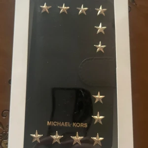  Mobilfodral iPhone 7 Michael Kors - Nytt Mobilfodral i tuff design ”MICHAEL KORS” tillverkat av Saffiano läder. magnetisk stängning med fack på insidan. Höjd 138,3mm Bredd:67,1mm Djup:7,1mm. (Nu kan ni se vilka mobiler förutom iPhone som passar) Detta fodral tillverkas inte längre så passa på att köpa det. (Swish föredras & kan ev mötas upp) 