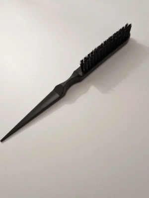 Svart tuperingsborste - Säljer en svart tuperingsborste med smal, spetsig plastända perfekt för att dela upp håret. Borsten har täta svarta borststrån och ett ergonomiskt handtag i plast. Perfekt för styling och att skapa volym.