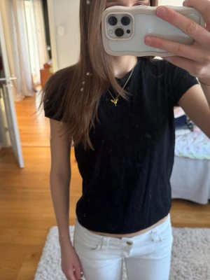 Svart basic t-shirt i bomull - En enkel svart t-shirt med rund hals och korta ärmar. Tillverkad i mjuk bomull som känns skön mot huden. Perfekt att matcha med jeans eller kjol för en clean och stilren look.