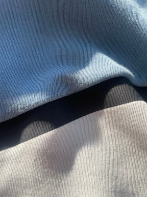 Ljusblå hoodie med zip-ficka - Snygg ljusblå hoodie med svart dragkedjeficka på ärmen och kontrasterande ljusgrå detaljer. Tillverkad i mjukt bomullsmaterial som känns skönt mot huden. Perfekt för dig som gillar stilrena och praktiska plagg.