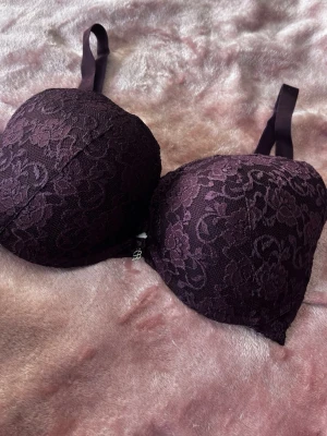 Mörklila push-up bh med spets - Snygg mörklila push-up bh från Cubus med vacker spets och vadderade kupor. Bh:n har justerbara axelband och en liten dekorativ berlock framtill. Perfekt för dig som vill ha både komfort och stil. Använd 1-3 gånger, fint skick. Storlek 80E nypris 249kr mitt pris 90kr ( pris går att diskutera) 🥰