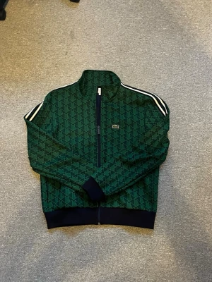 Lacoste zip - Snygg grön ziptröja från Lacoste som inte används längre då den är för liten. Den är i M men kan även passa S