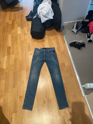 Blå slimfit Reaplay jeans  - Säljer ett par klassiska blå jeans från Reaplay Jeans med slim fit ben och snygga kontrastsömmar. Jeansen har fem fickor och coola detaljer på bakfickorna samt en brun läderpatch i midjan. Perfekta till en Grish  stil.