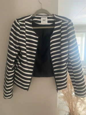 Randig kavaj från OBJECT, svart/vit - Snygg kavaj från OBJECT i svart och vitt med horisontella ränder. Modellen är öppen framtill utan knappar och har en rak, något kortare passform. Materialet är strukturerat och fodrat för extra komfort. Perfekt för att lyfta vilken outfit som helst.