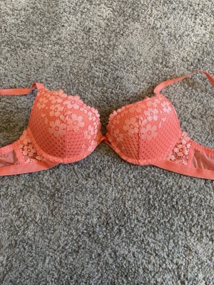 Korallfärgad spets-bh med blommönster - Snygg bh i korallfärg med blommig spets och justerbara axelband. bh:n är från dollarstore, som ny och bra kvalitet på den💕