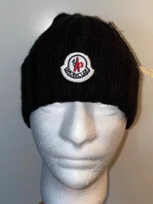 Moncler Mössa-Svart, One size - Helt ny. Fin replika med hög kvalitet. One size. Pris: 449kr. Först till kvarn. Skickas direkt inom 24h