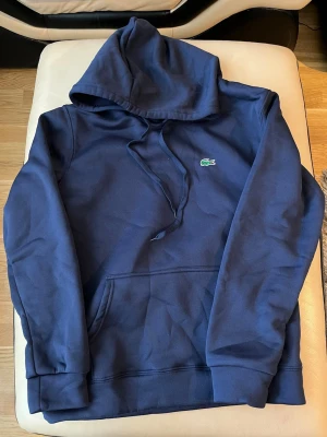 Lacoste hoodie - Säljer en riktigt skön hoodie perfekt för både sommarkvällar och våren.  Storlek M (true to size) och gjord i ett mjukt, bekvämt material som håller dig lagom varm. Obs Sista pris