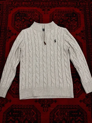 Ljusgrå kabelstickad tröja Polo Ralph Lauren - Snygg ljusgrå kabelstickad Polo Ralph Lauren quarter zip i mycket bra skick utan defekter 🔥  Storlek L på taggen men har krympt efter varm tvätt och sitter nu som EU S. Perfekt för våren och kyliga sommarkvällar. Pris går att diskutera 💯