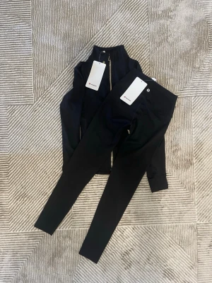Lululemon Define Nulu set, Strl. 2/xxs Tröja och byxor - Svart Färg - Super skick - Hej!   Jag säljer en väldigt snygg Lululemon Define set, storlek 2 i svart färg.  Allt är i superskick utan några slitage på märket eller andra defekter på materialet.  Tröjan och byxorna är väldigt mjuk och bekväm, vilket passar för dig som gymmar eller för sköna vardagar.  Kommer från en djur- och rökfritt hem. Fraktas alltid samma dag innan klockan 20, hör av er om ni undrar något!