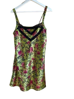 Lindex Grönt blommigt nattlinne med spets Xs-S - Snyggt nattlinne i glansigt grönt tyg med rosa och svarta blommor. Dekorerat med svart spets vid bysten och smala axelband. Perfekt för en bekväm och stilren look hemma. Bra skick, storlek Xs men S bra med.