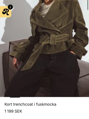Grön kort trenchcoat i fuskmocka nakd  - Stilren grön trenchcoat i fuskmocka med knytskärp i midjan. Säljer då jag beställde i två storlekar och glömt reutanera… prislapp är kvar och helt oanvänd nypris ligger på 1200kr