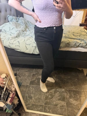 Svarta skinny jeans med hög midja - Säljer ett par svarta skinny jeans med hög midja och klassisk femficksdesign. Jeansen har smal passform hela vägen ner och stängs med knapp och dragkedja. Perfekta för dig som gillar en tight och stilren look.