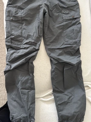 Grå cargobyxor från Parajumpers - Snygga grå cargobyxor från Parajumpers med stora fickor på sidorna och resår vid bensluten. Byxorna har en avslappnad passform och är tillverkade i ett lätt och slitstarkt material. Perfekta för en cool och avslappnad stil.