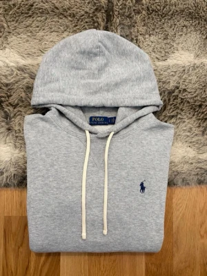 Ljusgrå Polo Ralph Lauren Fleece Hoodie - Storlek S - Använd ett fåtal gånger, pris kan diskuteras vid snabb affär. ( ändå defekten är 2 små hål på ryggen som inte syns vid användning, se bild 7).