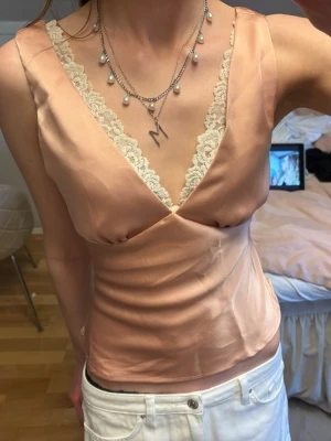 Persikofärgad satinlinnetopp med spets - Jättefin blus/top i satin, tyvärr gör sig färgen inget bra på mig… nyskick!!