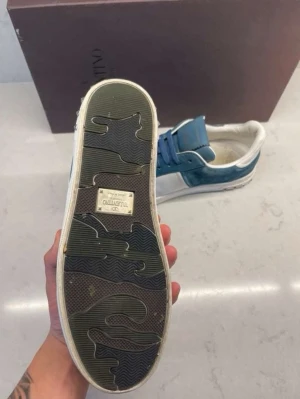 Saint Laurent camo sneakers - Snygga sneakers från Saint Laurent med klassiskt camouflagemönster i grönt, brunt och svart. Skorna har svarta snören, beige sula och diskret Saint Laurent-logga på sidan och plösen. Perfekta för dig som vill sticka ut med en streetstyle-look.