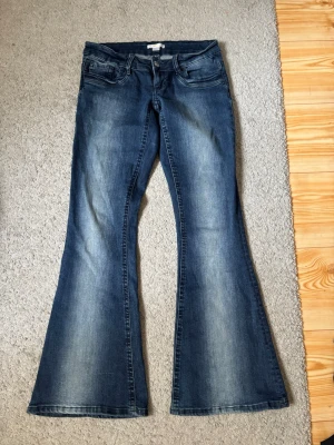 Low waisted bootcut jeans från Gina Tricot - Snygga blå bootcut jeans. Jeansen har en låg midja och är utsvänga. Tillverkade i denim med en skön känsla och cool tvätt. Är endast använda en gång, de är i ny skick. Sitter super bra! De är helt slutsålda på Gina och de säljs nypris för 360 kr.