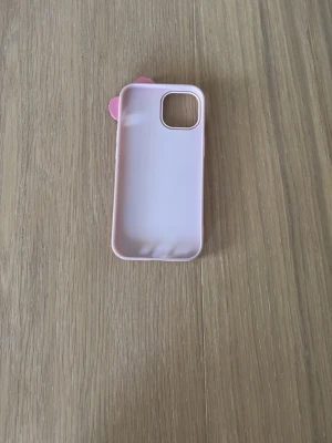 Rosa mobilskal med glittrig rosett - Sött ljusrosa mobilskal med en glittrig rosett upptill. Skalets material är mjukt silikon som ger bra grepp och skydd. Passar perfekt för dig som vill ha en gullig och personlig look på mobilen. Har en liten fläck därför ett bättre pris