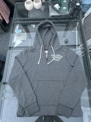 Hollister hoodie – grå half zip (S) - Clean Hollister hoodie i grå melerad färg med half zip och liten logo framtill 🔥  Perfekt basic hoodie för sommarkvällar eller en clean everyday fit. Sjukt enkel att styla och sitter riktigt nice.  • Storlek: S • Skick: mycket bra • Half zip framtill • Mjuk fleece-insida • Bomull/polyester-blandning • Normal passform  Passar perfekt till jeans, cargos, shorts eller mjukisbyxor. Enkel men fett clean hoodie som alltid funkar.