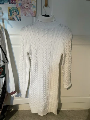 Vit kabelstickad poloklänning - Säljer en lång, vit kabelstickad klänning med polokrage och långa ärmar. Klänningen har ett klassiskt flätmönster och ribbade muddar vid hals, ärmslut och nederkant. Perfekt för kalla dagar och supermysig att bära. Från New Yorker, har glömt priset och den finns inte kvar på hemsidan men jag tror den var 179-199kr. Storlek L men den är tajt. OANVÄND för den var för liten för mig. Utan defekter.
