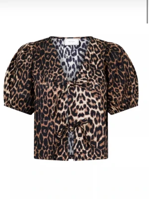 Leopardmönstrad blus med puffärm - Snygg leopardmönstrad blus från Neo Noir med korta puffärmar och två knyt framtill. Blusen har v-ringning och är tillverkad i ett glansigt, mjukt material som ger en lyxig känsla. Knappt använd!