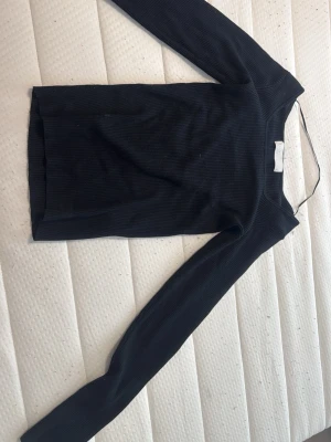 Svart ribbad långärmad topp  - Snygg svart långärmad med ribbad struktur. Modellen är tight. Perfekt att styla med jeans eller kjol för en clean look. Kommer ej ihåg vilket märke 