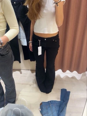Svarta bootcut jeans från Gina Tricot - Säljer ett par svarta bootcut jeans från Gina Tricot med låg midja och klassisk femficksdesign. Jeansen har en snygg utsvängd passform och är perfekta för en trendig och avslappnad look. Materialet är stretchigt för extra komfort.